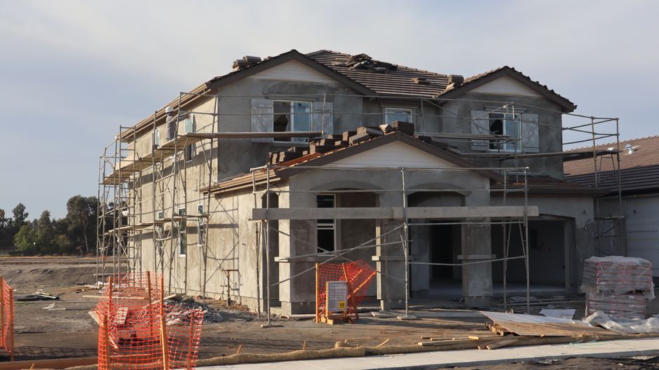 Two-story house with large windows being worked on