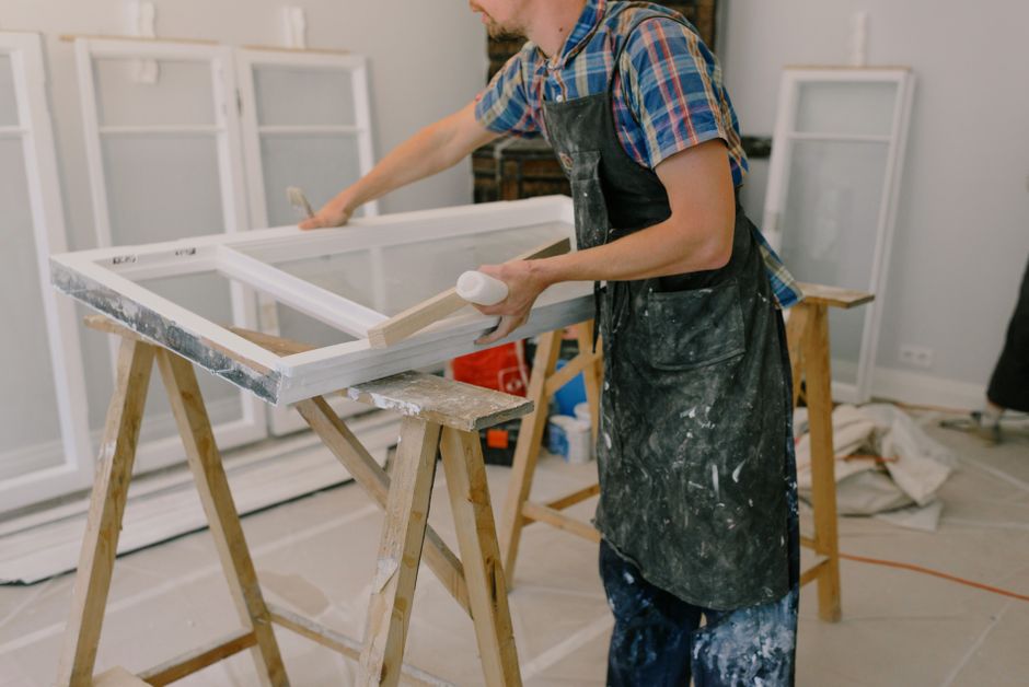 Craftsman standing beside a white-framed window on a workbench