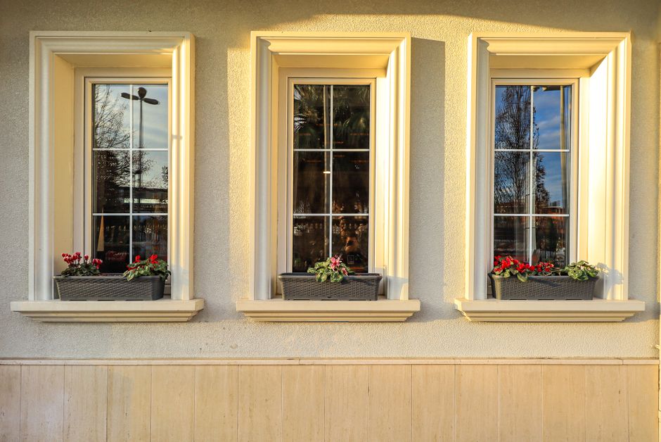 Three windows with flower pots on the sills in evening light