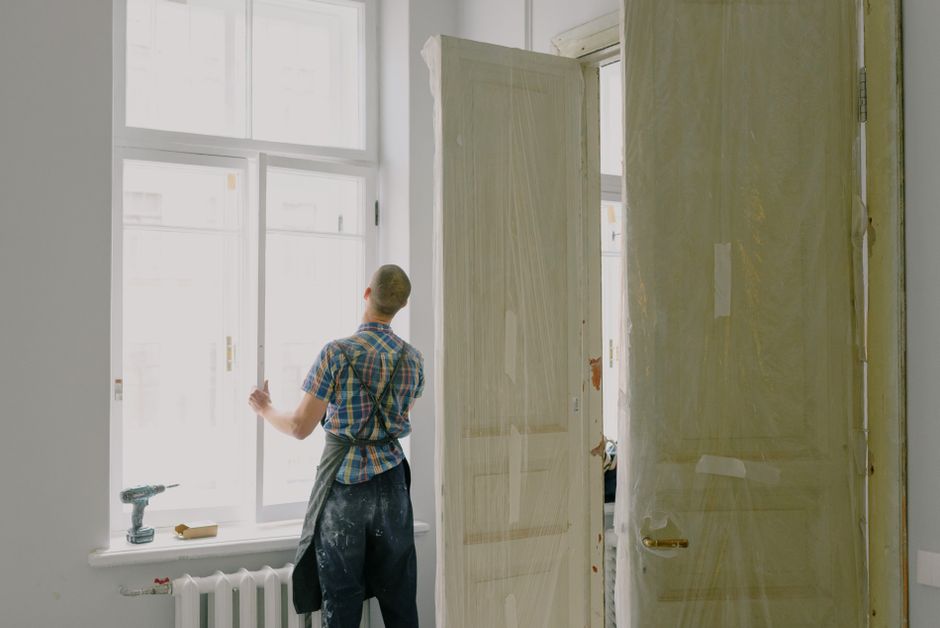 Installer setting a window into a wall opening with a drill nearby