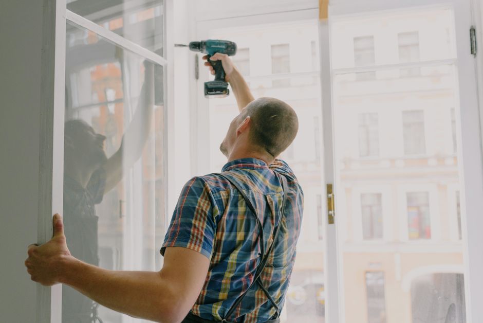 Installer fastening a window frame in an opening during a replacement job